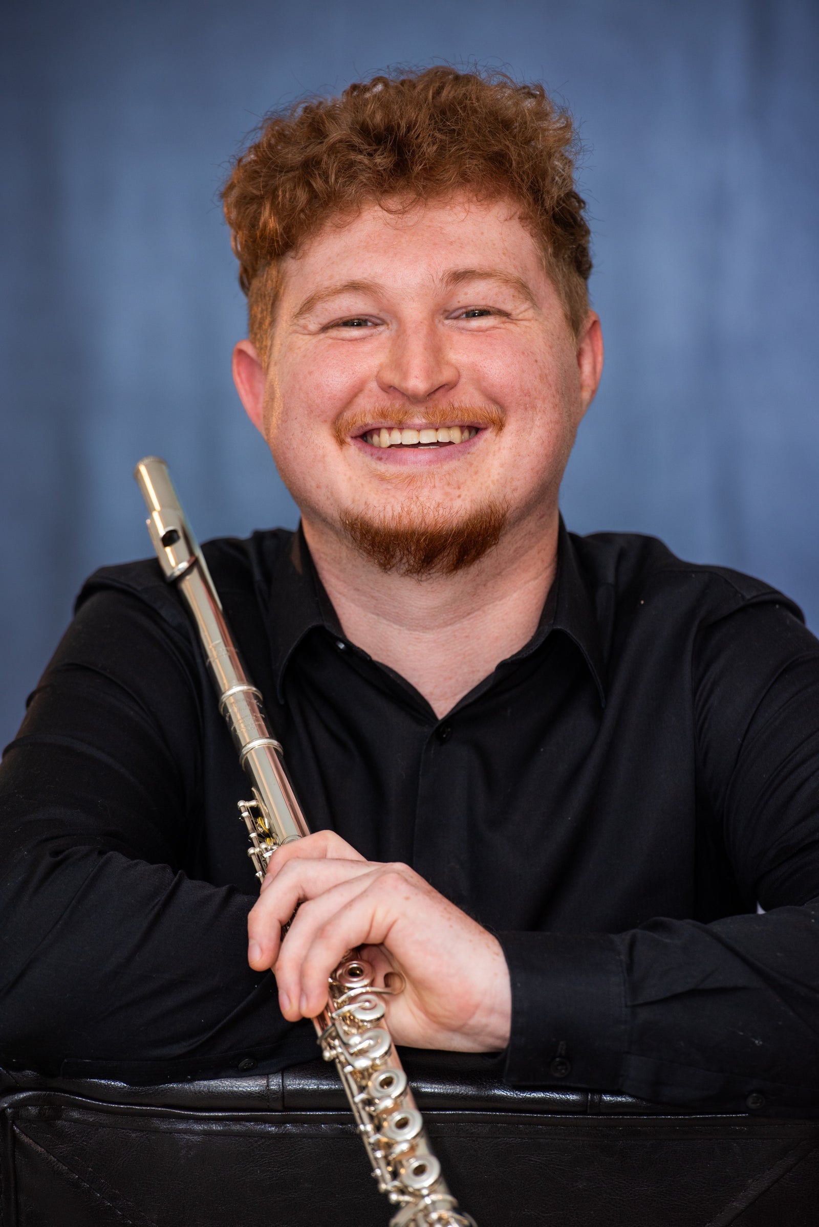 Man holding a flute against a blue background
